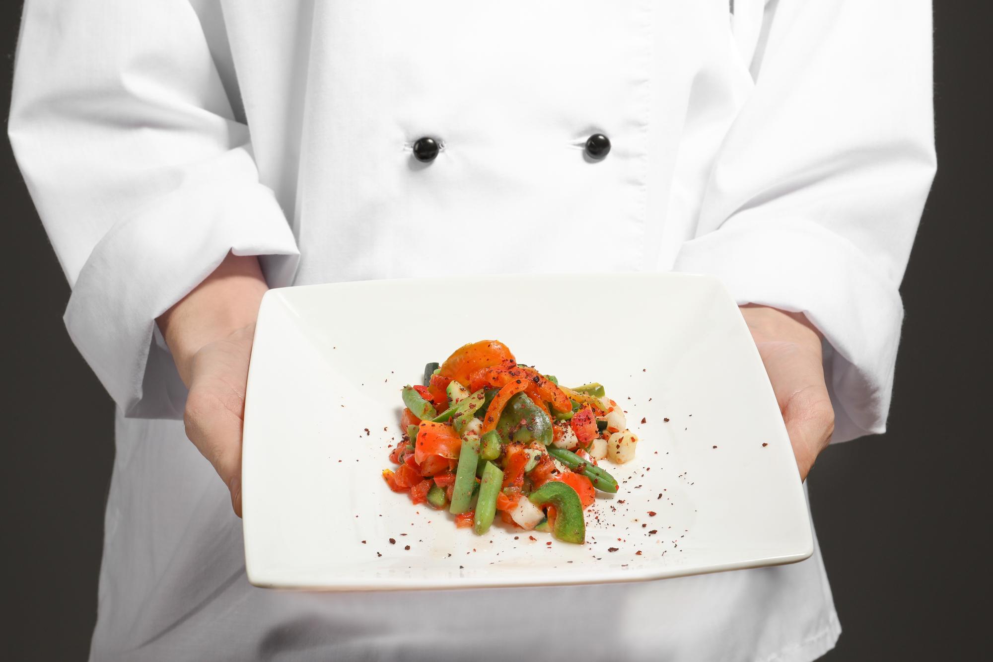 Chef che prepara un piatto in cucina luminosa